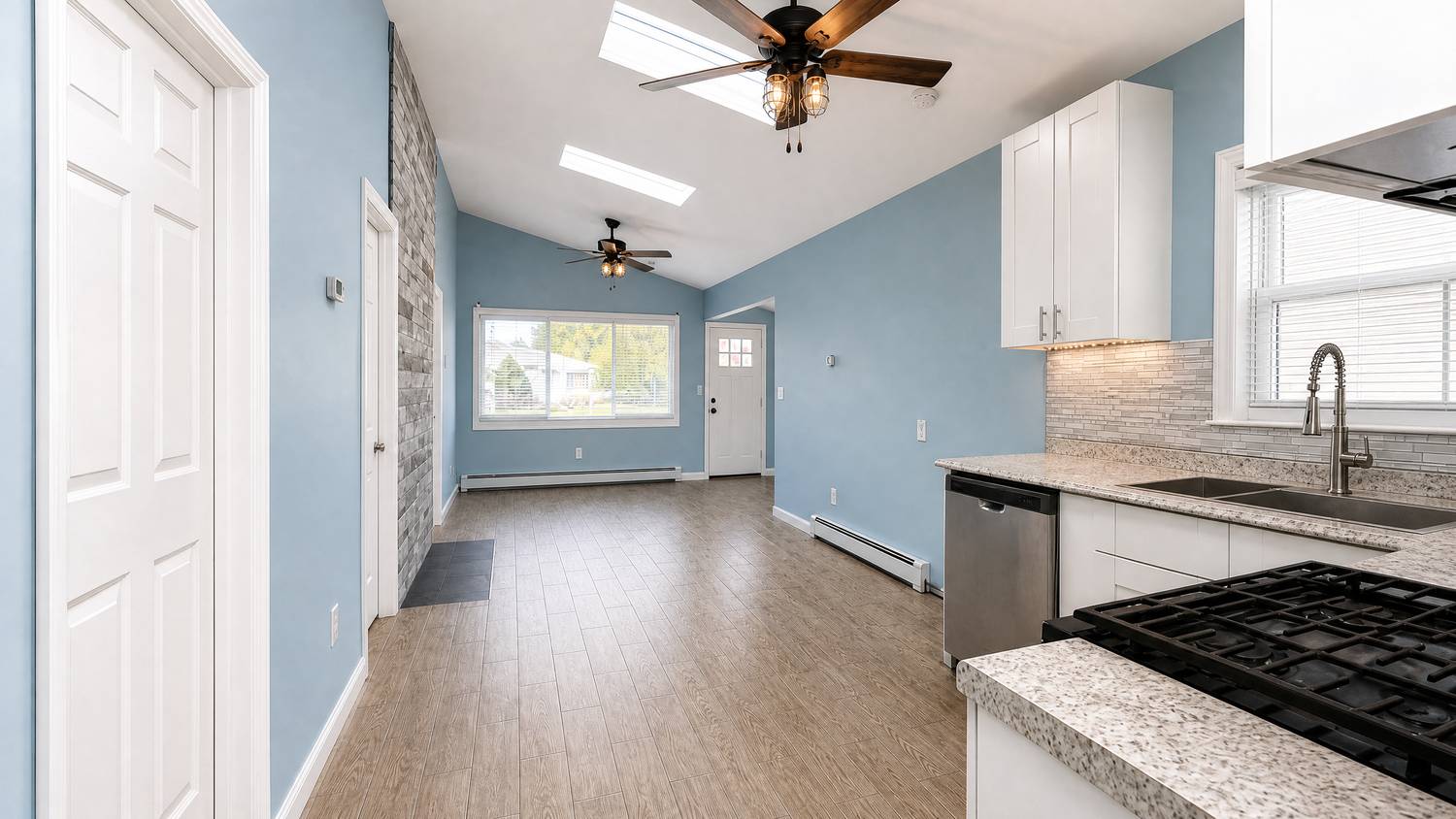 Open kitchen and living area with vaulted ceiling and skylights